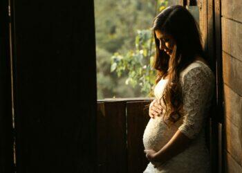 Pregnant woman standing by window (Unsplash | Mel Elias)