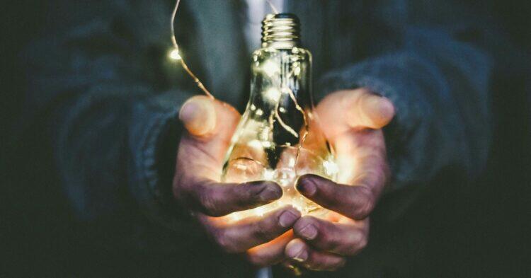 Person holding a lit lightbulb (Unsplash | pavement_special)