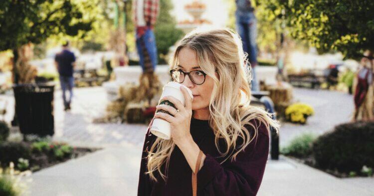 Woman drinking coffee outdoors (Unsplash | Caleb George)