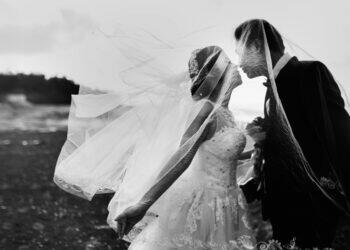 Black and white wedding photo with bride and groom posing on a hill (Unsplash | Hisu lee)