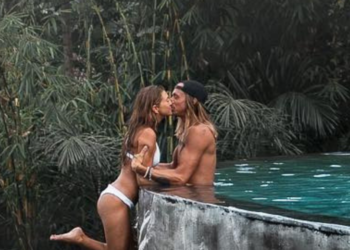 The controversial photo posted by @positravelty on Instagram where Kelly seems to be dangling off the cliff of a roof pool.