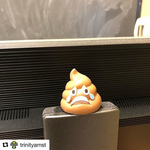 A toy that looks like a crying poop emoji sits in front of a computer