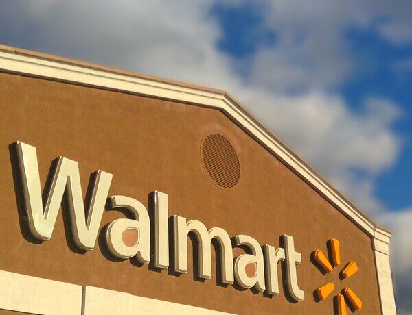An image of a Walmart storefront in front of a clouded sky.