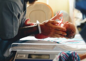 person wearing gray shirt putting baby on scale