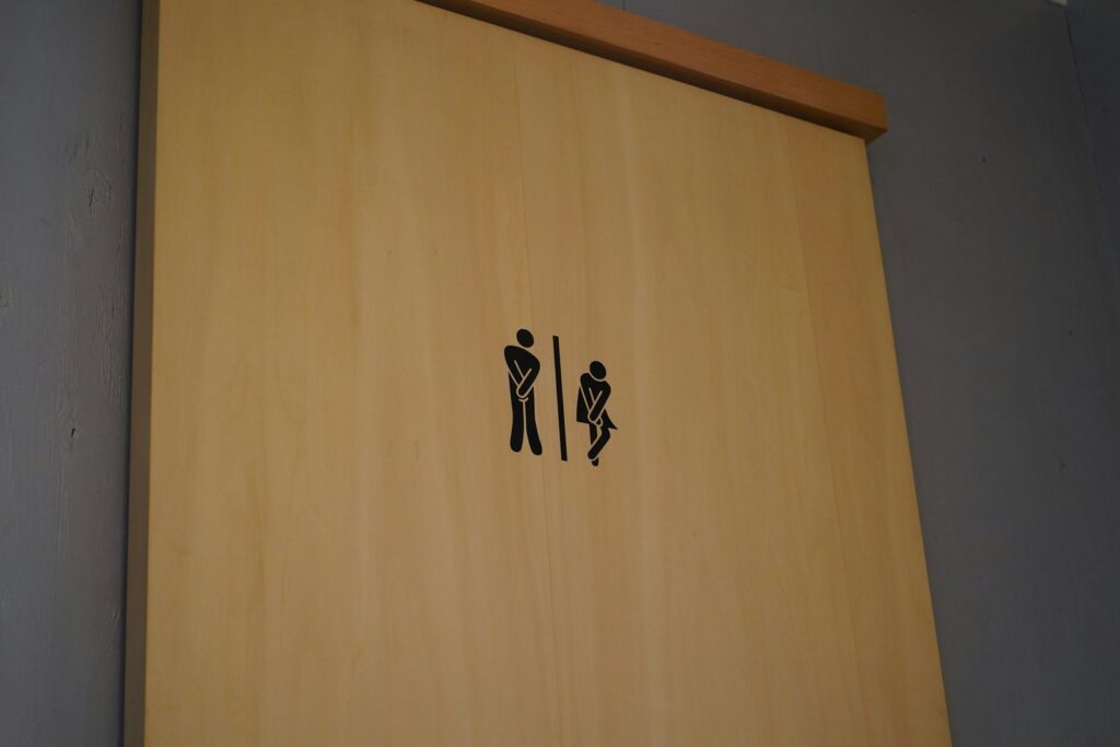 a wood door to a bathroom featuring an image of two stick figure people