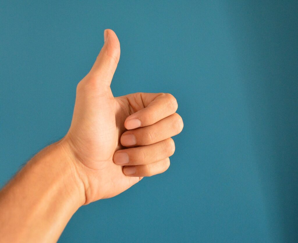 a hand doing a thumbs up in front of a blue background