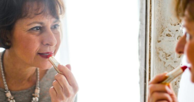 Photo of Older Woman Applying Lipstick In Front of the Mirror