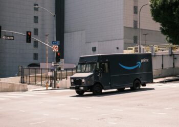 blue and white Amazon van parked near white building during daytime