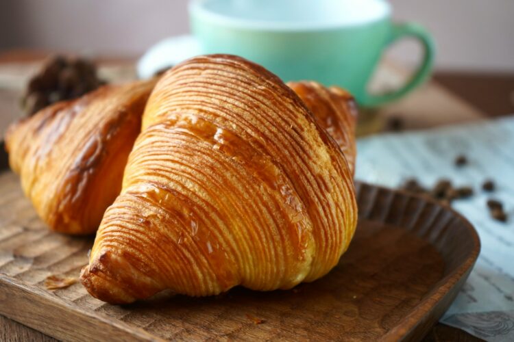 two croissants sitting on top of a wooden tray
