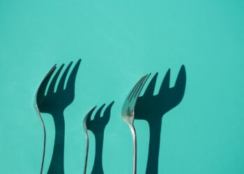 three gray metal forks casting shadow on green surface