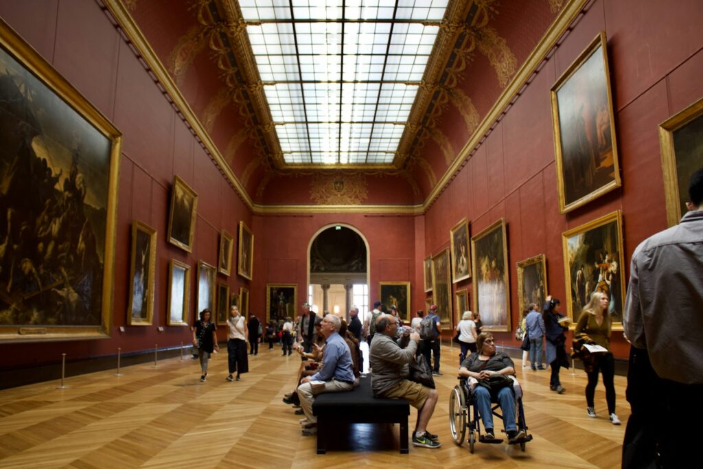 A group of people standing in a room filled with paintings