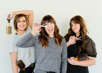 three women holding scissors and brush