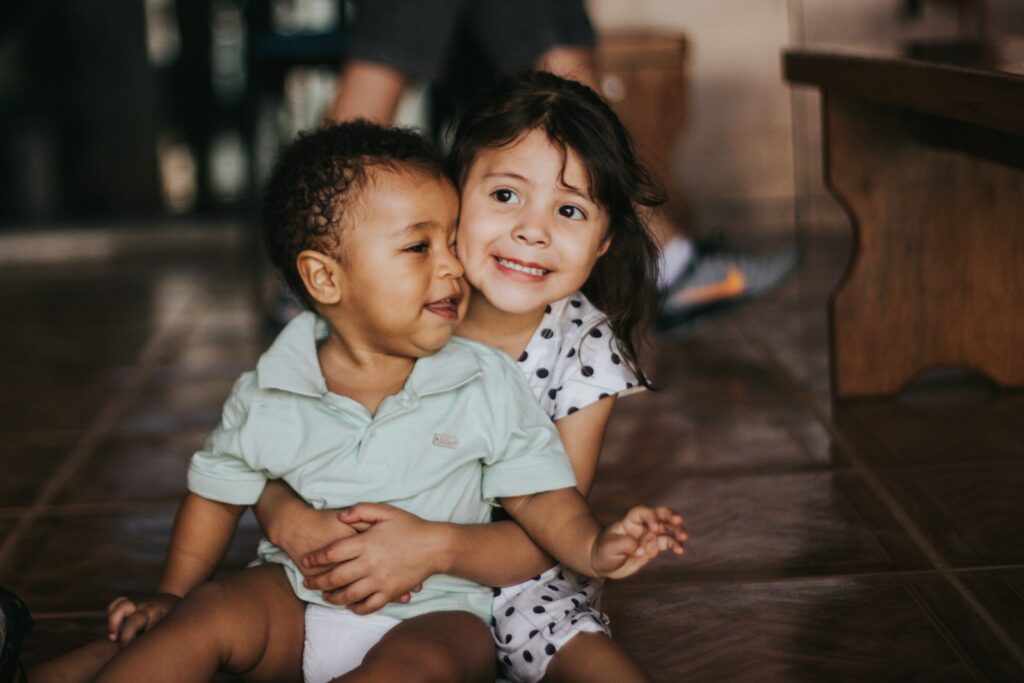 selective focus photography of a toddler girl hugging baby boy