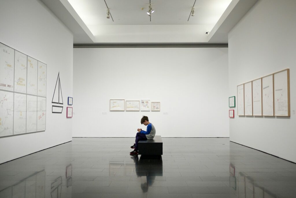 man sitting near museum painting
