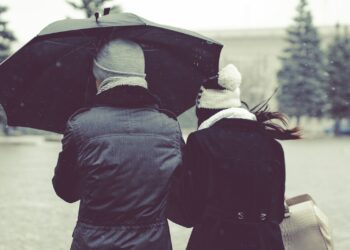 back view photography of two person under umbrella on snowy day
