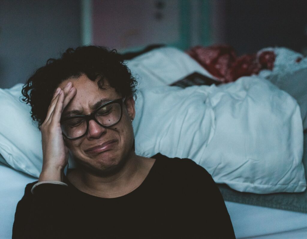 a person crying beside a bed with white sheets