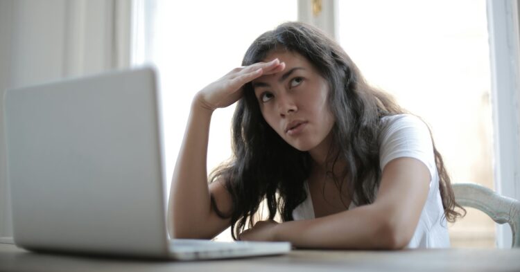 young annoyed female sitting in front of laptop