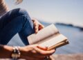 hands holding a book with water background