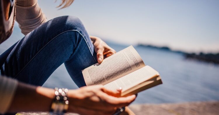 hands holding a book with water background