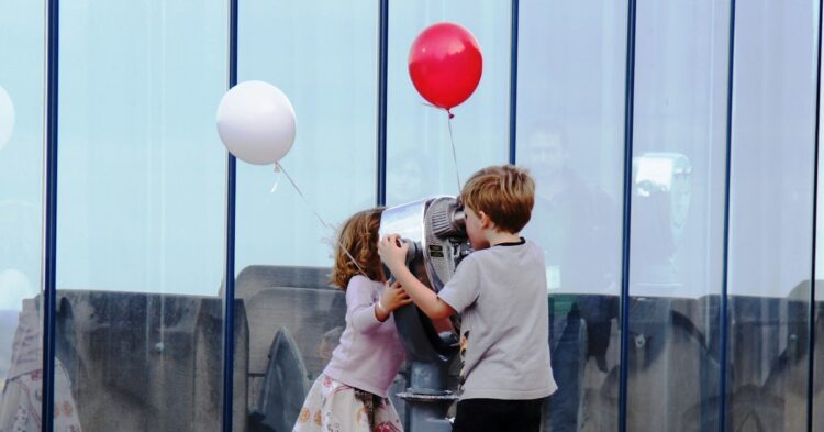 a couple of kids that are standing on a pole