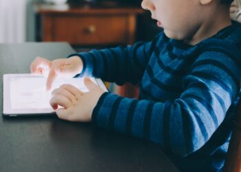 boy sitting on chair beside table using tablet computer