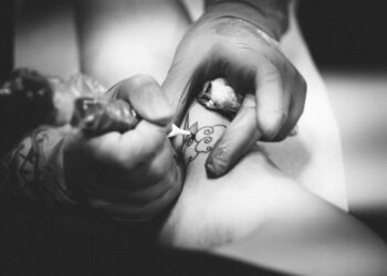 person doing flower tattoo on leg