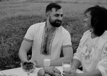 a man and a woman sitting at a table in a field