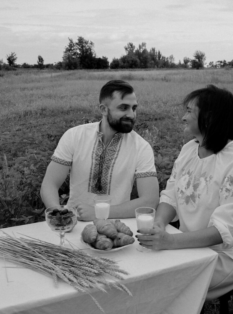a man and a woman sitting at a table in a field