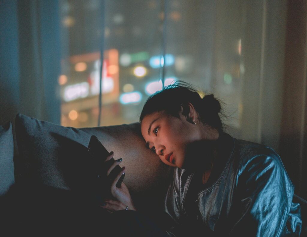 Photo Of Woman Using Mobile Phone in front of a window at night