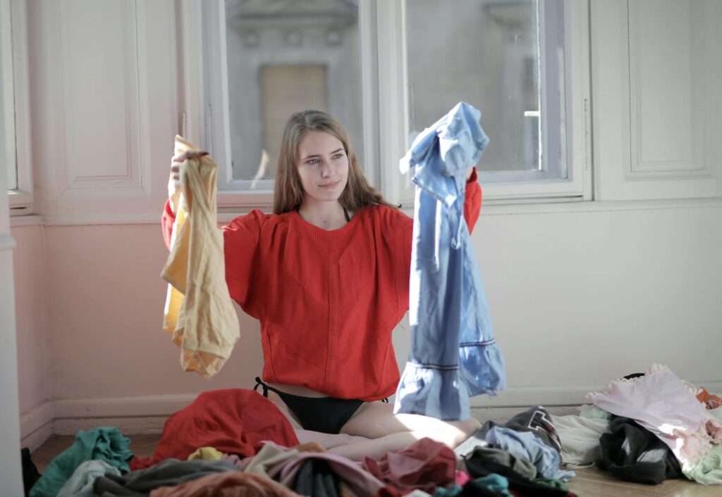 Woman in Red Long Sleeve Shirt Holding Her Clothes