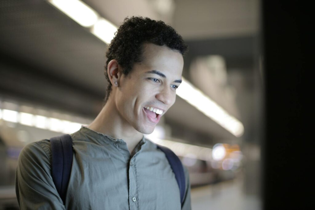 Excited ethnic man interacting with touch screen display in city
