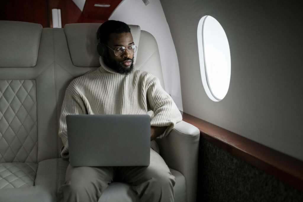 Man in White Sweater Sitting on Couch Using Macbook