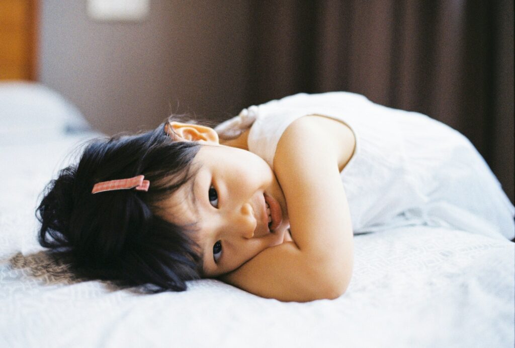 girl in white tank top lying on bed