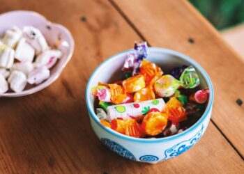 two bowls of colorful candy on a wooden table top