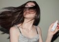 woman holding a spray bottle with flowing hair in the air
