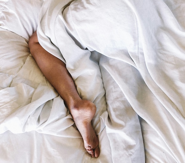 leg peeking out of bed sheets