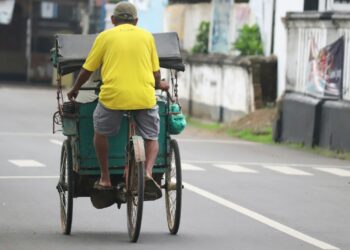a man riding on the back of a green cart