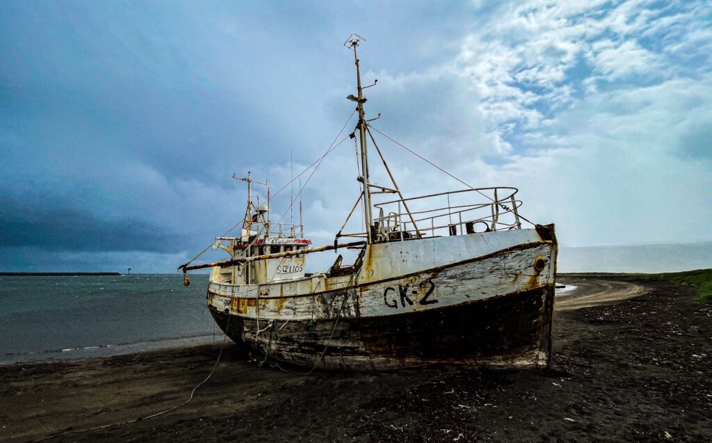 a rusted boat sitting on top of a beach