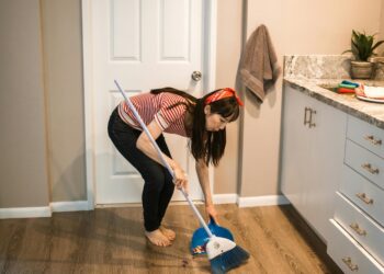 woman cleaning the floor with a dust brush and pan
