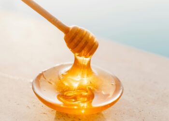 Dipping wooden honey spoon in liquid honey