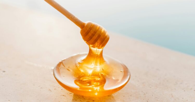 Dipping wooden honey spoon in liquid honey