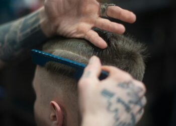 man with tattoos cutting another man's hair
