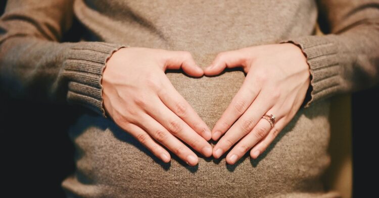 hands on a pregnant stomach forming a heart