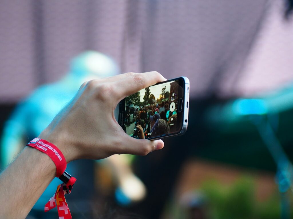 person using black smartphone at a concert