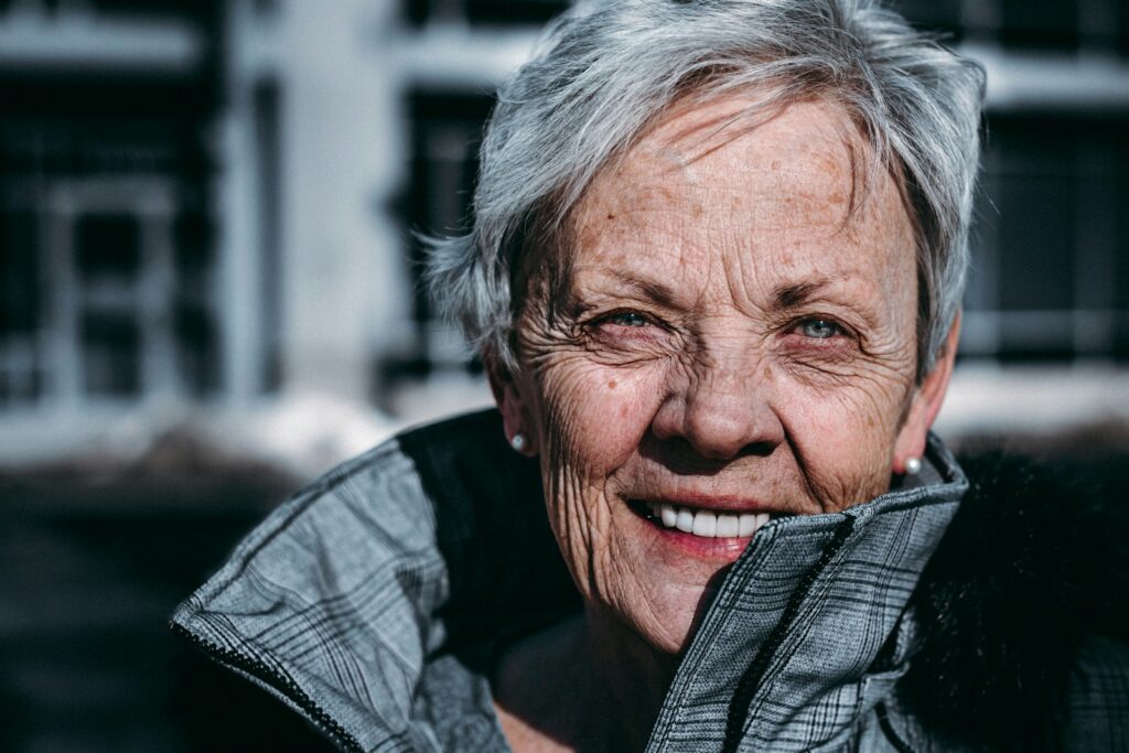 an older smiling woman in a gray jacket