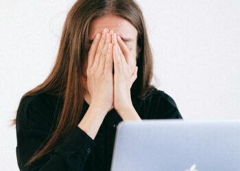 Woman With Hands on her Face in front of a Laptop