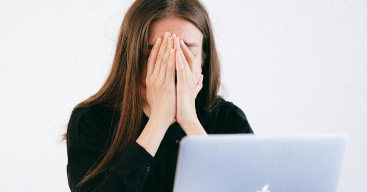 Woman With Hands on her Face in front of a Laptop