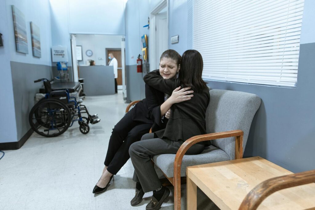 Women in Hugging Each other while Sitting on the Sofa