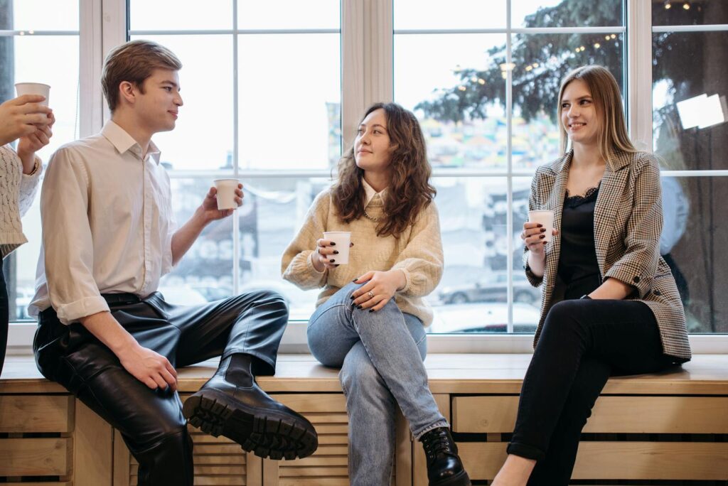 People Sitting near the Glass Windows while Holding Paper Cups