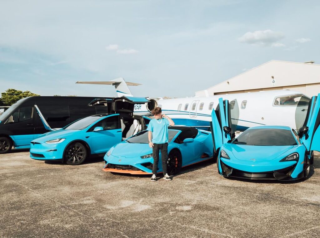 Jack Doherty standing in front of cars and a jet